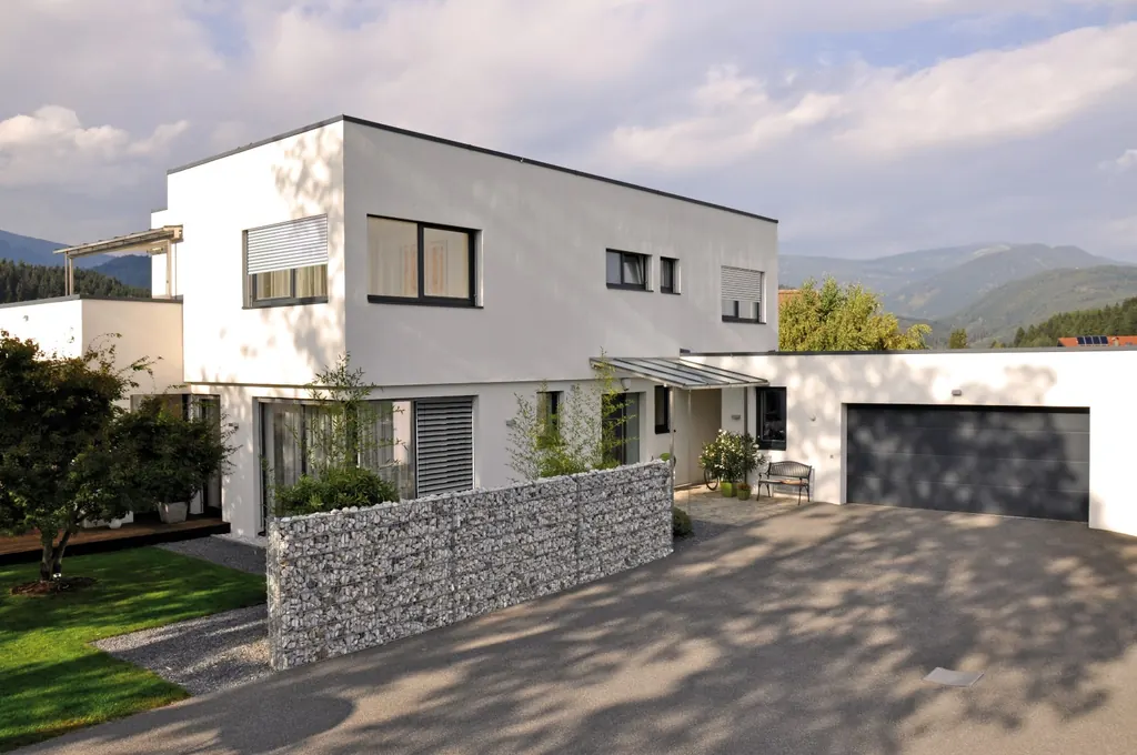 Vivienda unifamiliar moderna de fachada blanca con carpinterías oscuras